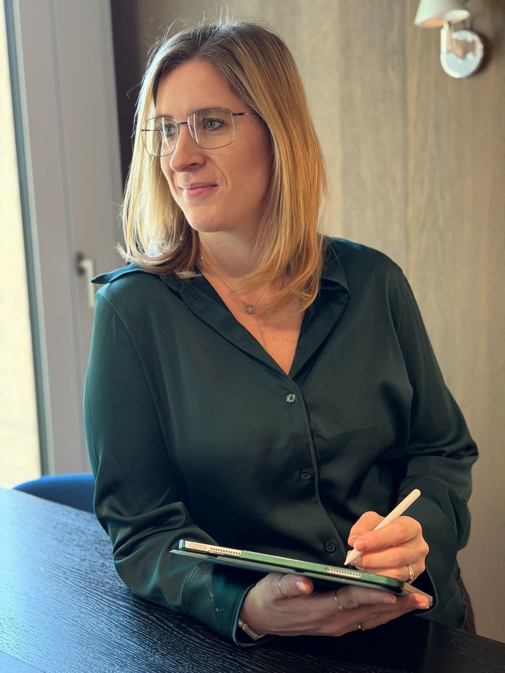 Carolin schaut nachdenklich zur Seite, in der Hand ein Tablet mit Stift